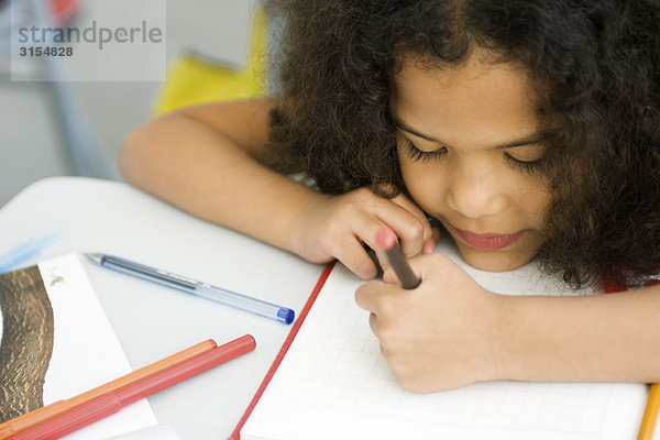 Kleines Mädchen ruht Kopf auf Schreibtisch  Zeichnung auf Millimeterpapier
