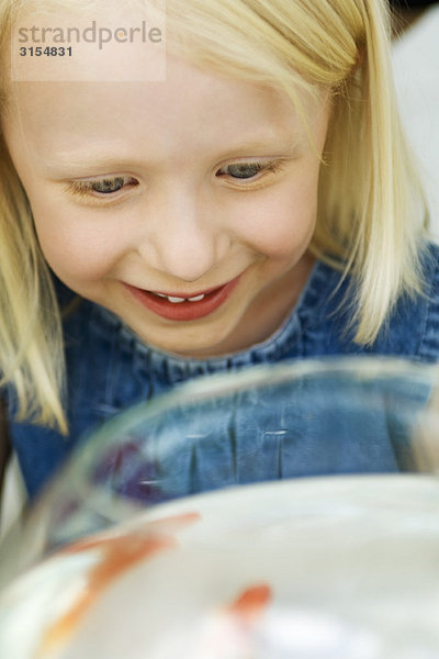 Kleines Mädchen schaut auf Goldfisch in der Schale  Hochwinkelansicht