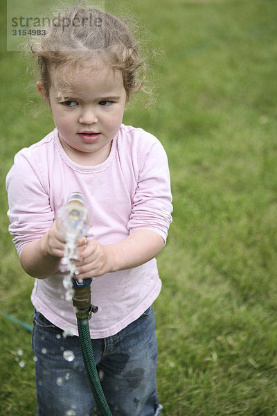 Little girl holding a garden hose