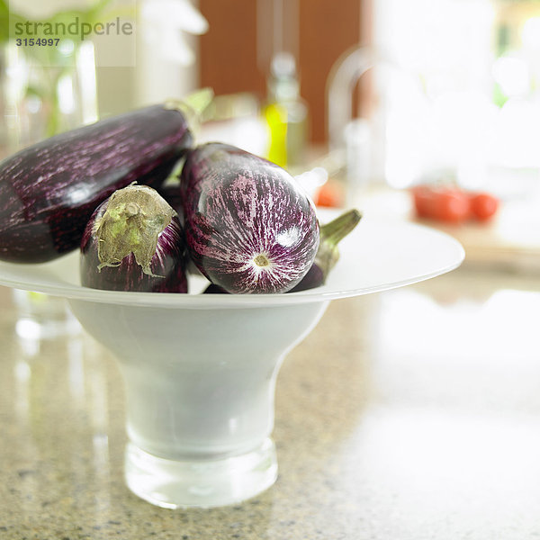 Close up of eggplant in a white bowl on a kitchen counter