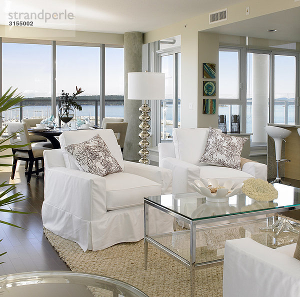 Living room with white furniture and sea view in background