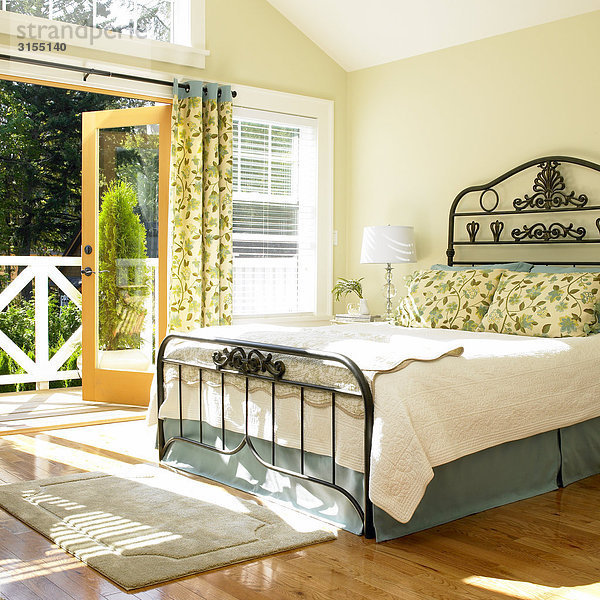 Sunny bedroom with doors open to deck  Victoria  British Columbia