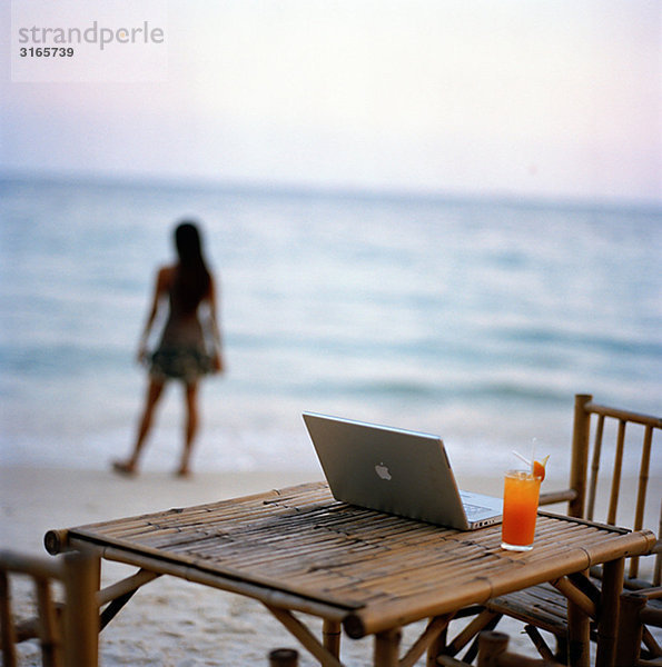 Eine junge Frau mit einem Laptop auf dem Strand  Thailand.