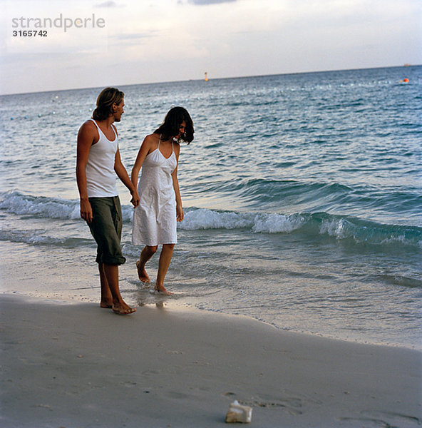 Ein junges paar gehen Hand in Hand am Strand  Thailand.