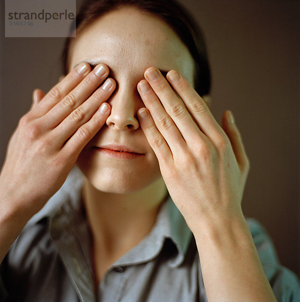 Portrait einer Frau mit ihr die Hände auf ihre Augen.