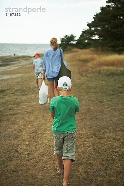 Mutter und Söhne zu Fuß auf einem Strand Gotland Schweden.