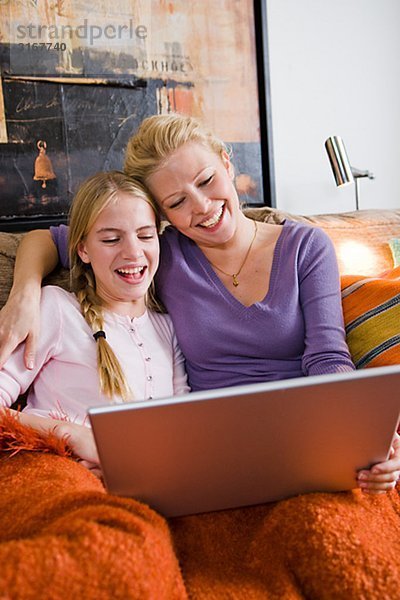 Mutter und Tochter mit einem Laptop in eine Couch  Schweden.