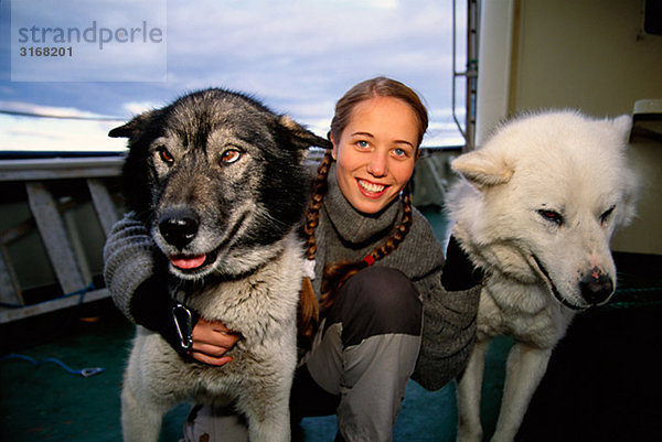 Eine Frau und zwei Hunde auf einem Boot Svalbard.