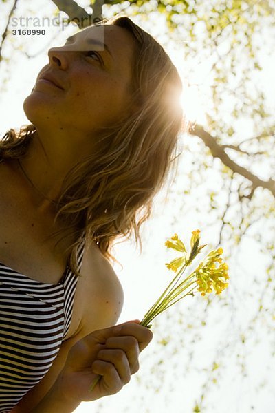 Porträt von s Woman smelling eine Blume.