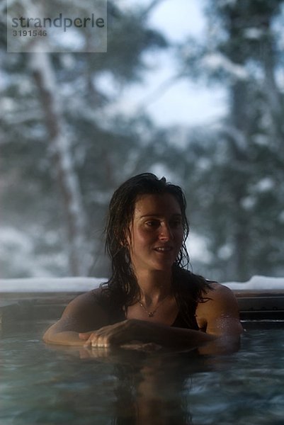 Eine Frau mit ein heißes Bad außerhalb im Winter  Schweden.