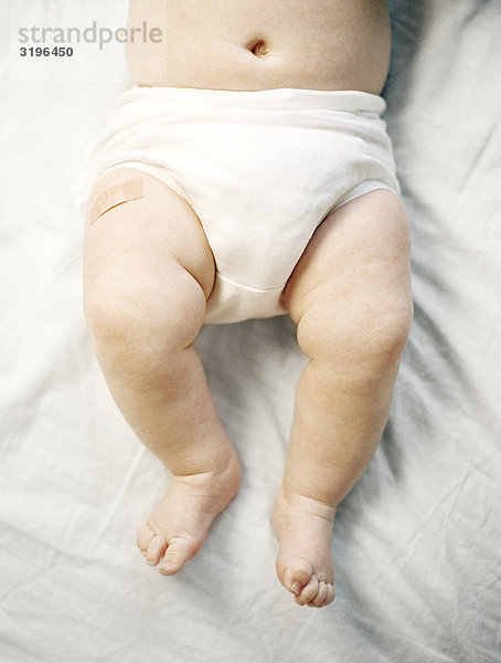 Ein Pflaster auf einem Bein auf ein Baby.