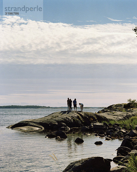 Vier Menschen stehen auf eine bloße Klippe  Harstena  Gryt Archipels  Östergötlands  Schweden.