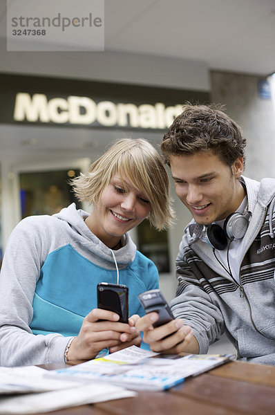 Zwei Teenager amüsieren sich über Handyfotos  Frontalansicht
