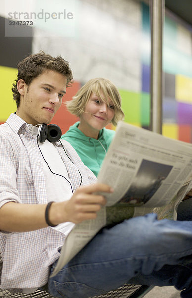 Teenagerpaar Zeitung an U-Bahnstation lesend  Flachwinkelansicht