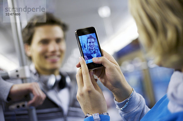 Junger Mann wird in U-Bahn mit Mobiltelefon fotografiert  Schrägansicht
