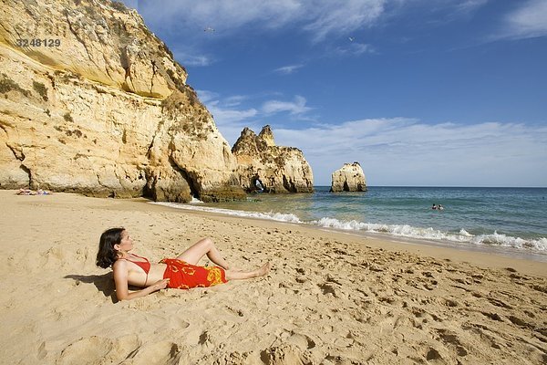 Frau liegt am Strand  Praia dos Tres Irmaos  Algarve  Portugal
