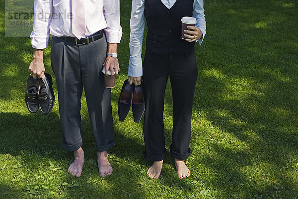 A barfuß Geschäftsmann und ein barfuß geschäftsfrau stehend auf Gras  Stockholm  Schweden.