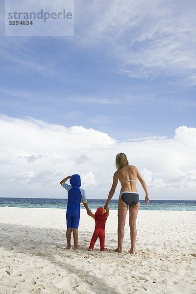 Mutter zu Fuß an einem Strand mit ihren zwei Kindern  den Malediven.