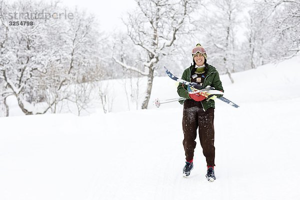Frau trägt Ski in winterlichen Landschaft  Schweden.