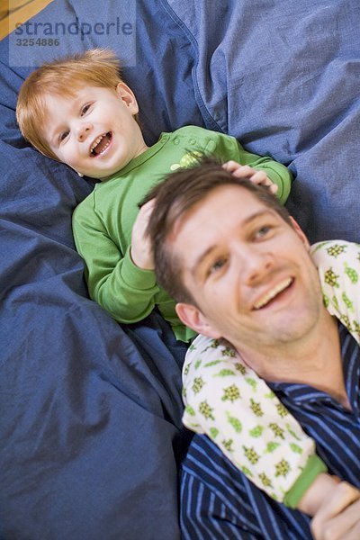 Vater und Sohn lacht in einem Bett  Schweden.