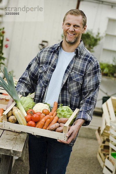 Mann mit einen Kiste voller Gemüse.