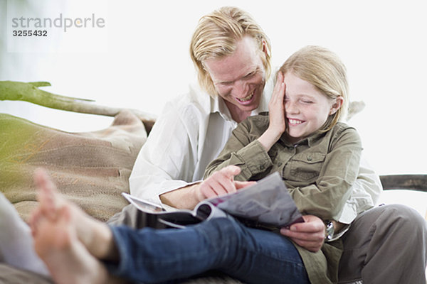 Vater und Tochter beim Lesen einer Zeitschrift