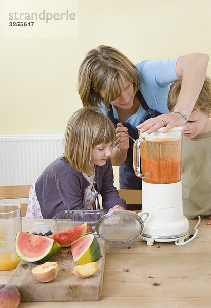 Junge  Mädchen und Mutter  die Fruchtsmoothies machen.
