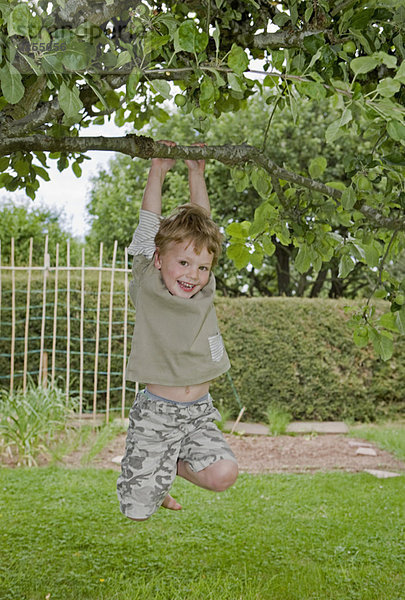 Junge am Baum hängend