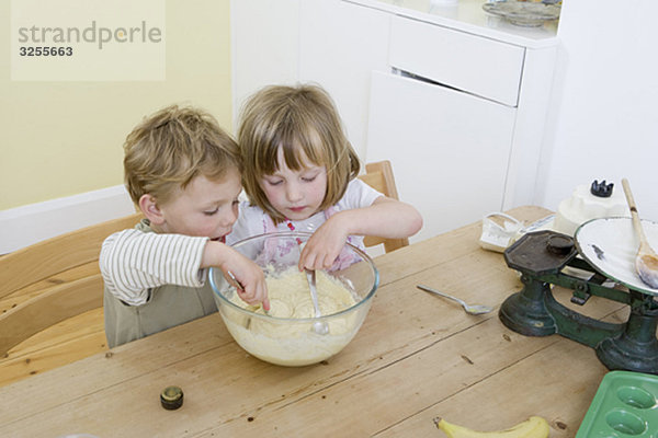 Junge und Mädchen mischen Kuchen