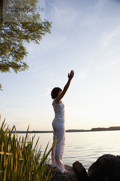 Frau führt Yoga am See durch