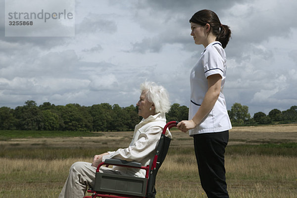 Ältere Frau im Rollstuhl mit Krankenschwester
