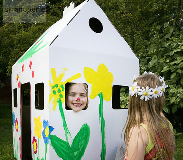 Mädchen spielen mit einem Papp-Wendy-Haus