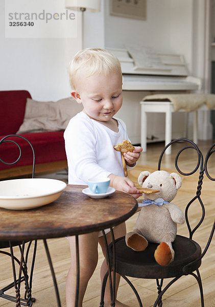 Kleinkind mit seinem Teddy auf der Teeparty