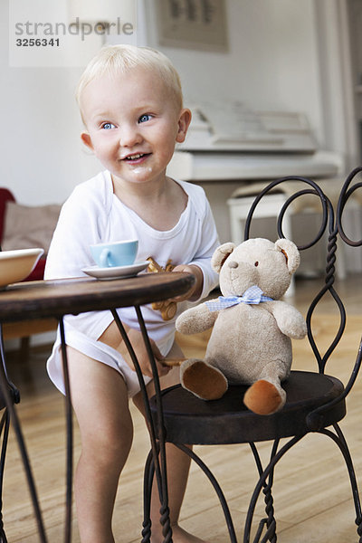 Kleinkind mit seinem Teddy auf der Teeparty