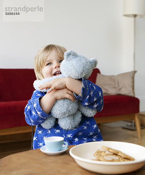 Ein Junge  der seinen Teddybären kuschelt.