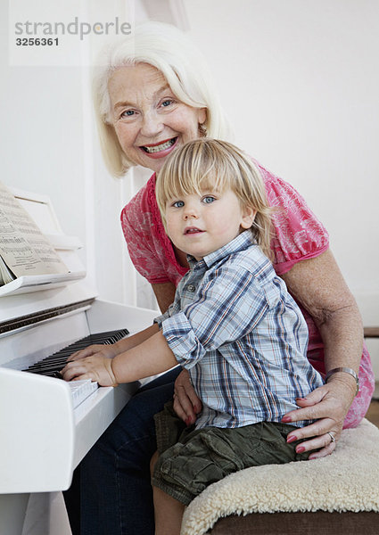 Oma und Enkel sitzen am Klavier