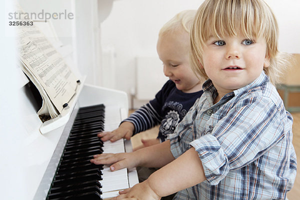 Zwei Kleinkinder am Klavier sitzend