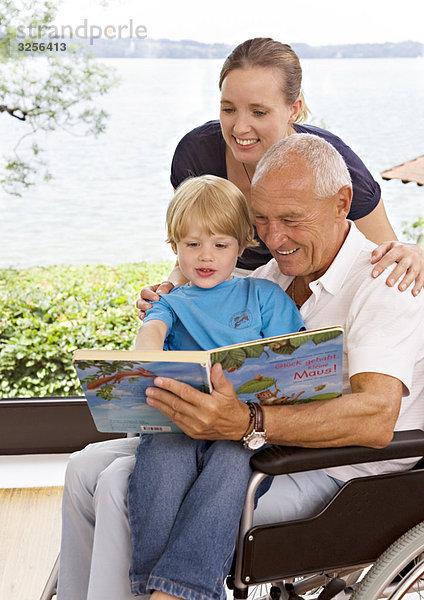 älterer Mann  der dem Jungen das Buch vorliest.