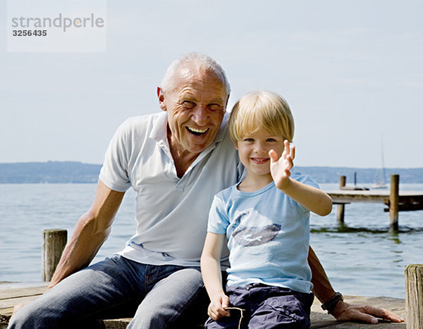 Junge mit Großvater am Pier am See