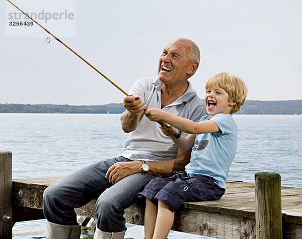 Junge fischen mit Großvater am See