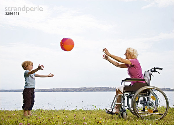 Junge spielt Ball mit älterer Frau