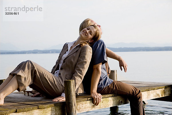 Frau und Mann sitzen auf dem Pier am See