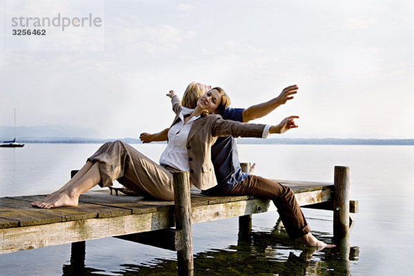 Frau und Mann sitzen auf dem Pier am See