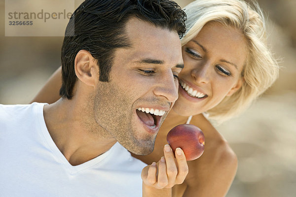 Ein Weibchen füttert einen lateinischen Mann mit einem Apfel.