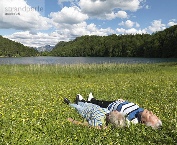 Seniorenpaar im Feld am See liegend