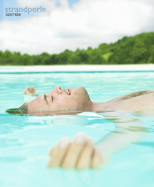 junger Mann  der im Wasser schwimmt