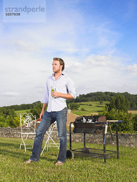 Mann beim Grillen vor der Haustüre