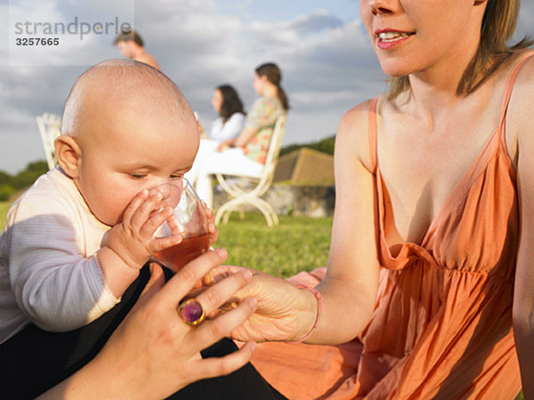 Babytrinken aus dem Glas der Mutter