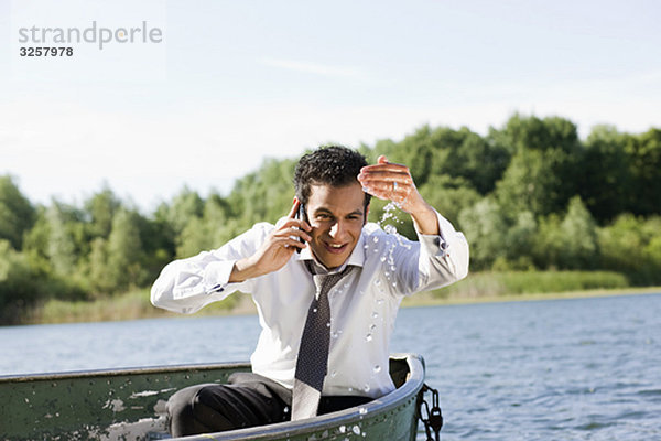 Geschäftsmann am Telefon im Ruderboot