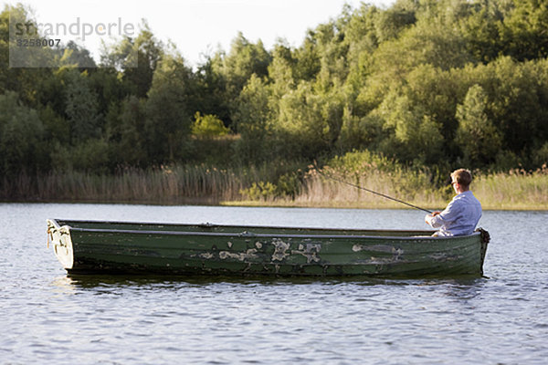 Mann fischt im Ruderboot